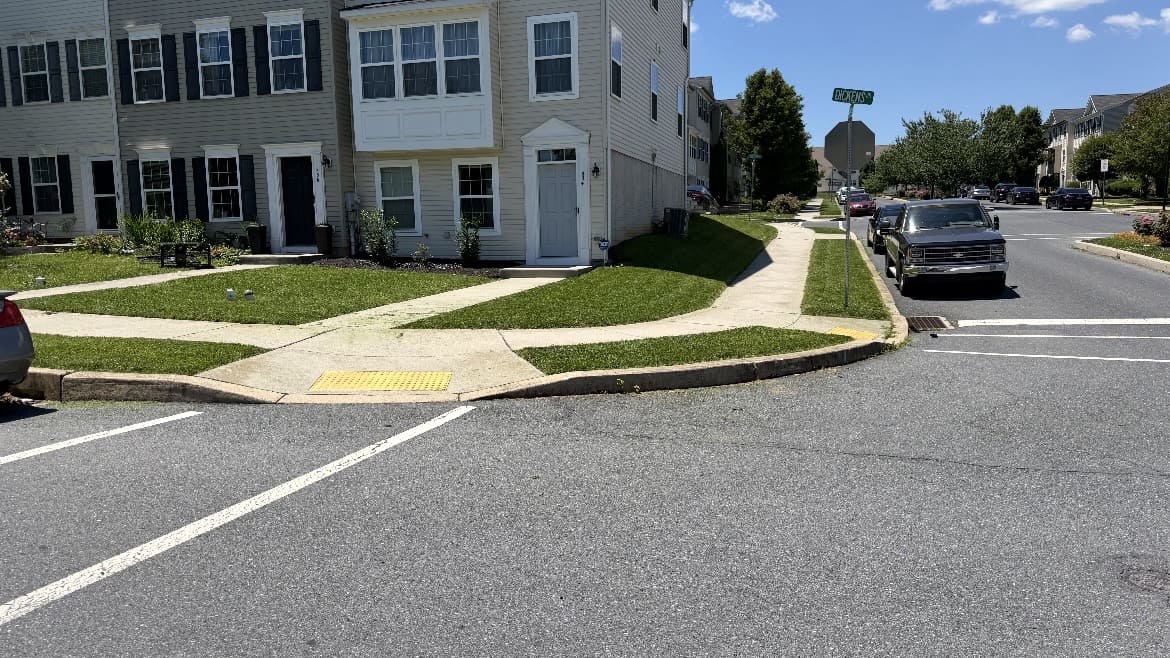 Corner lawn and curved sidewalk beside a residential building; business gallery photo, location unspecified