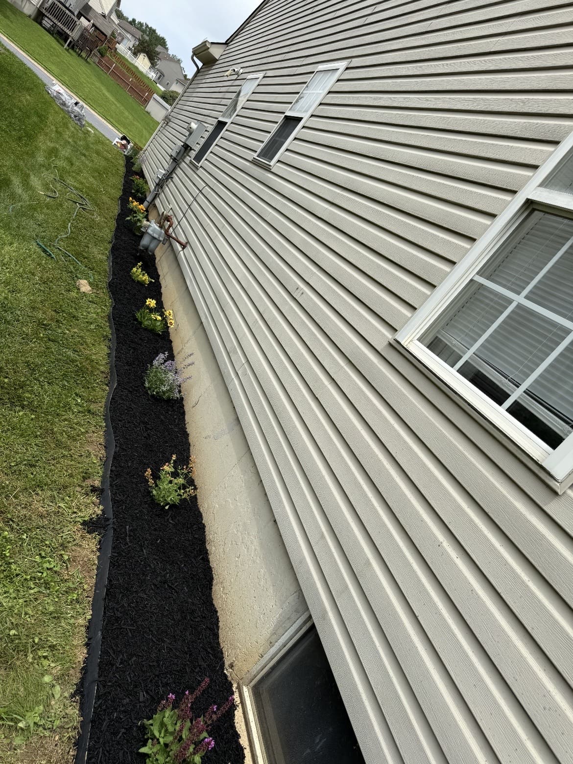 Narrow mulched bed along house siding; business gallery photo, location unspecified